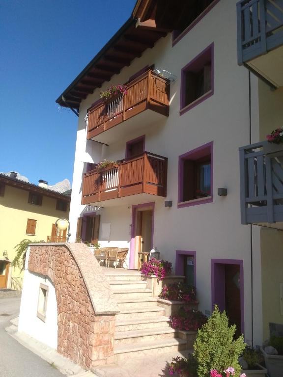 a white building with wooden balconies and stairs at Appartamenti Osti Sansoni Mariarosa in Andalo