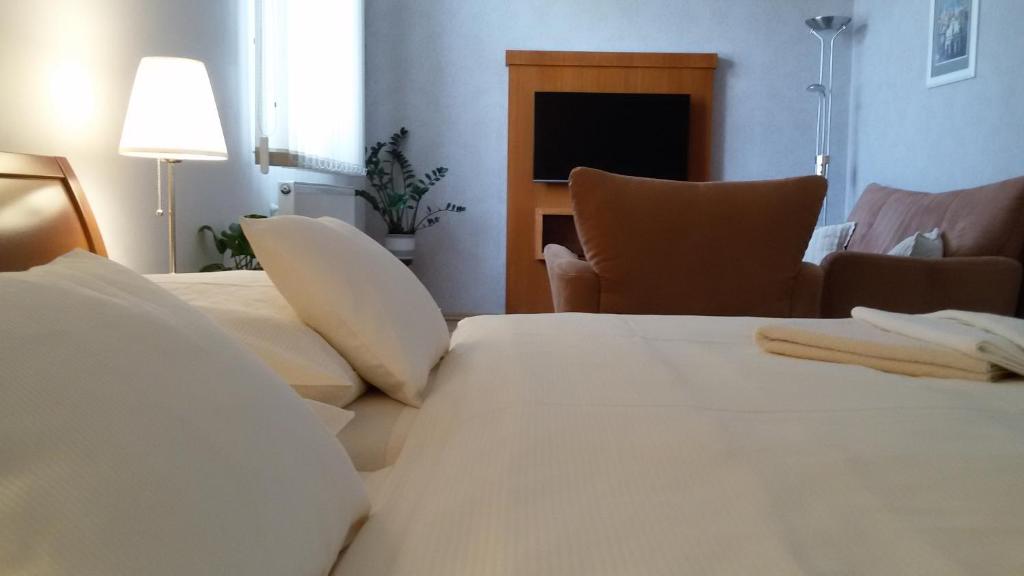 Habitación de hotel con cama con sábanas y almohadas blancas en Pension U Labe, en Hradec Králové