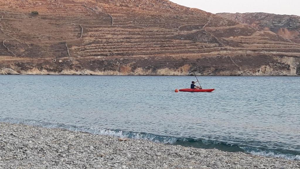 a man in a red boat in the water at Serifos Dream Houses near the sea in Ganema