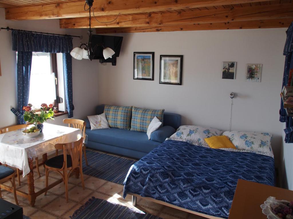 ein Wohnzimmer mit einem blauen Bett und einem Tisch in der Unterkunft Kellerstöckl Prantner & Haus Wohlauf in Rechnitz
