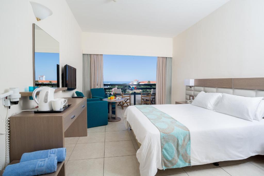 um quarto de hotel com uma cama e uma secretária com uma televisão em Avanti Hotel em Pafos