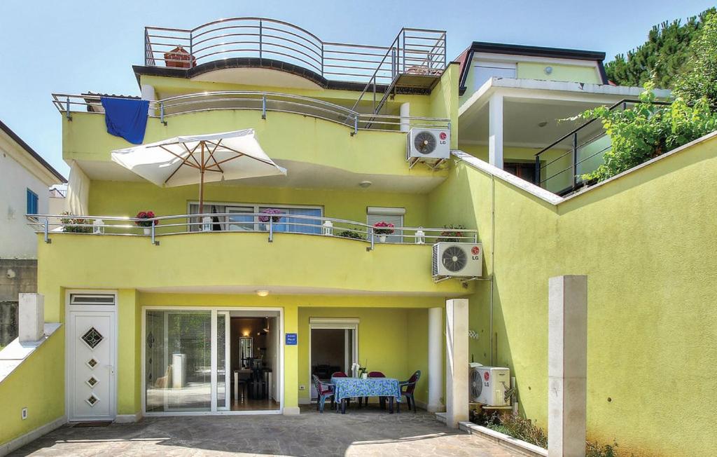 a yellow house with a balcony and a table at Apartment Katarina in Crveni Vrh