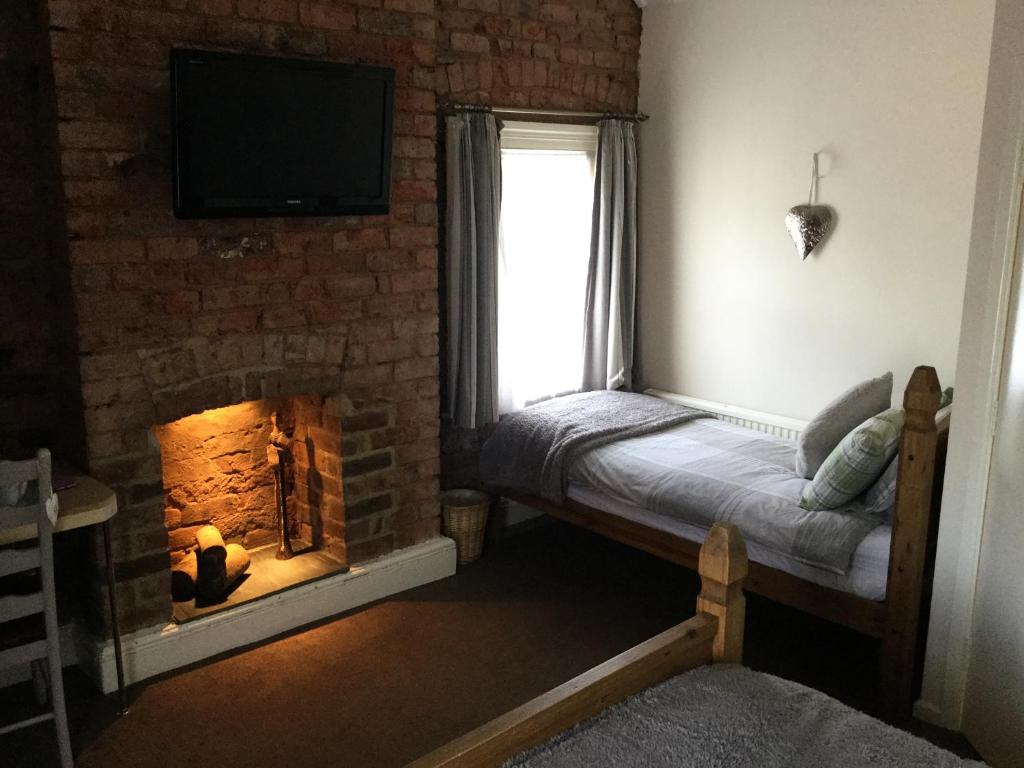 a bedroom with a fireplace with a television and a window at The Huntsman in Cheadle