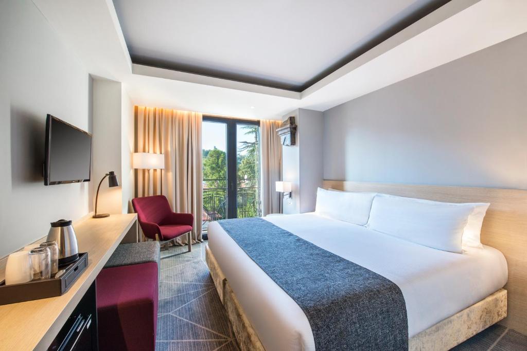 クタイシにあるBest Western Kutaisiの大きなベッドと赤い椅子が備わるホテルルームです。