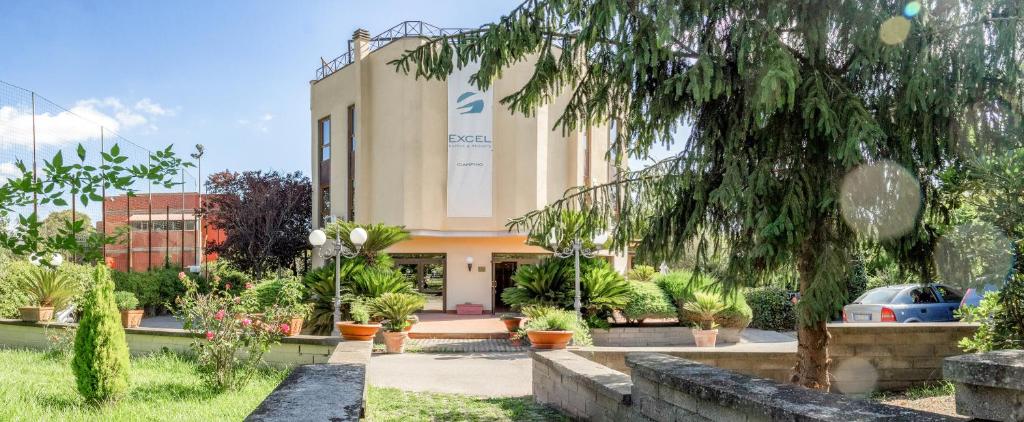 un bâtiment avec des plantes en pot devant lui dans l'établissement Excel Hotel Roma Ciampino, à Marino