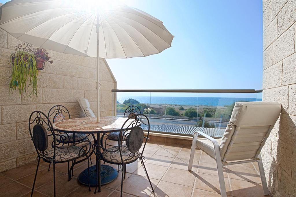 a patio with a table and chairs and an umbrella at Nahariya Beachfront in Nahariyya