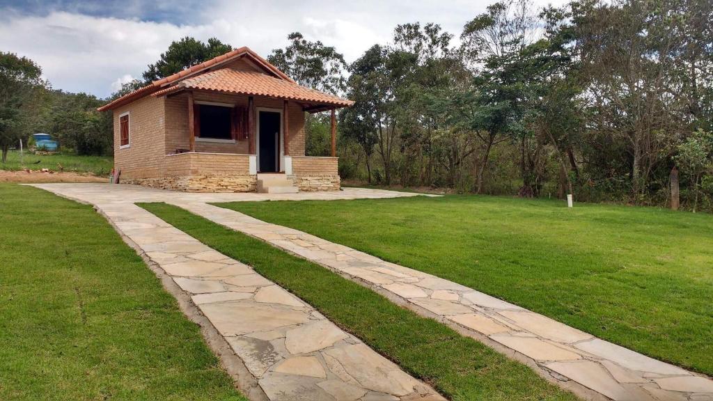 a walkway leading to a small house in a field at Chalé Primavera - Eubiose in São Thomé das Letras