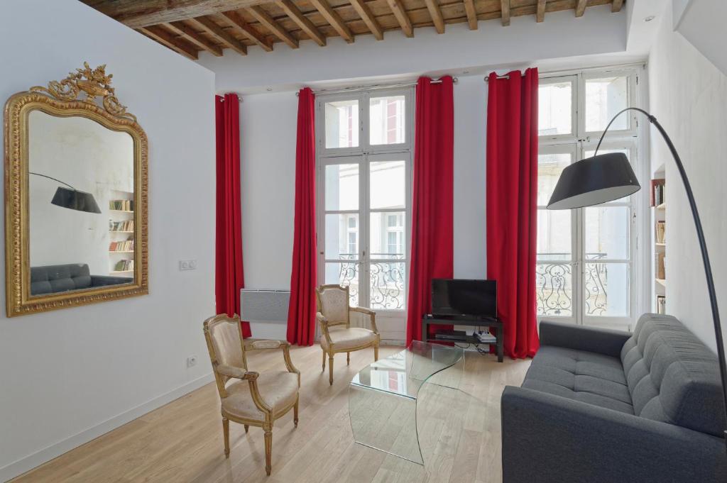 a living room with red curtains and a couch and a mirror at L'Argenterie, Apparts de charme climatisé parking gratuit in Montpellier