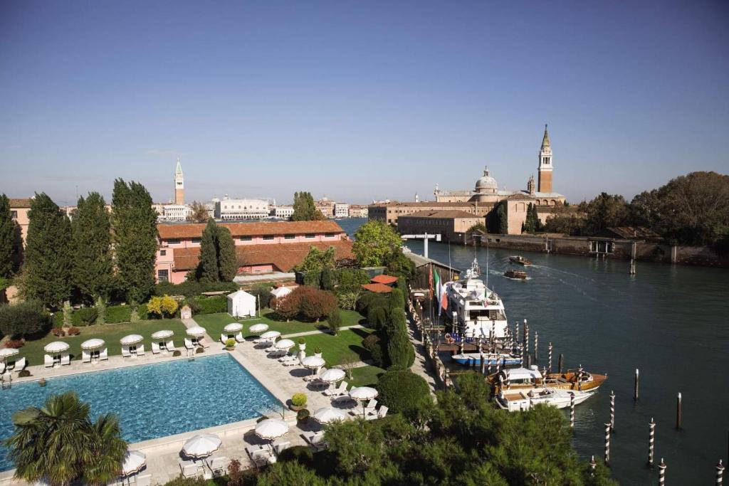 une grande piscine à côté d'une rivière avec des bateaux dans l'établissement Hotel Cipriani, A Belmond Hotel, Venice, à Venise