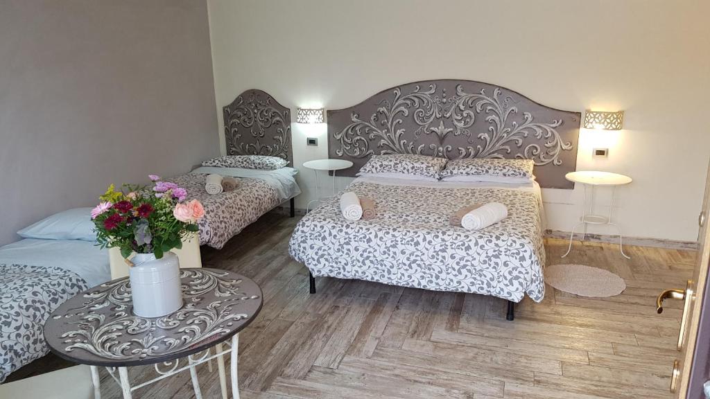 ein Schlafzimmer mit 2 Betten und einem Tisch mit Blumen in der Unterkunft B&B La Tartaruga in Pregnana Milanese