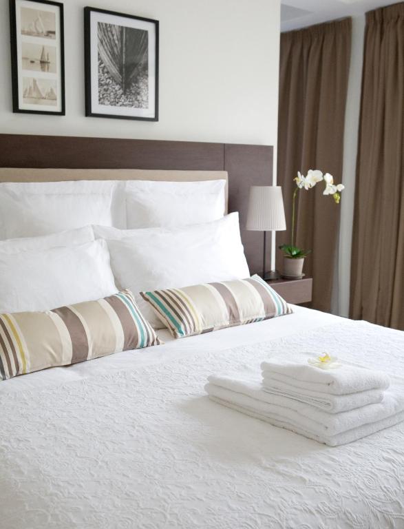 a bedroom with a white bed with towels on it at Sandy Beach Hotel & Spa - ex Sentido in Larnaca