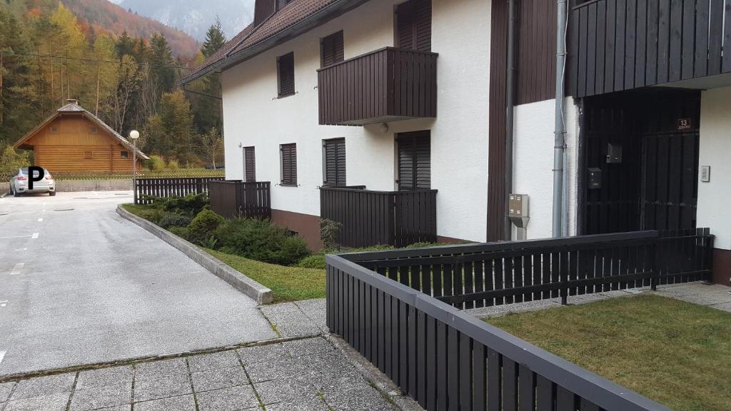 a white building with a black fence next to a driveway at Apartment HM in Gozd Martuljek