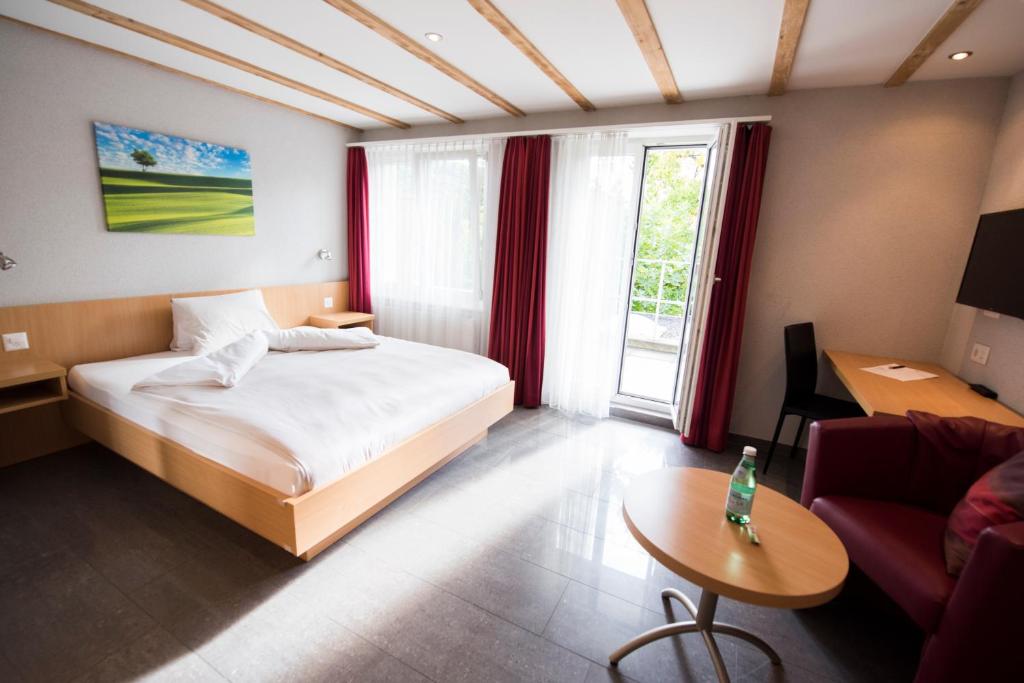a bedroom with a bed and a table and a couch at Hotel Restaurant Neuhaus in Nussbaumen