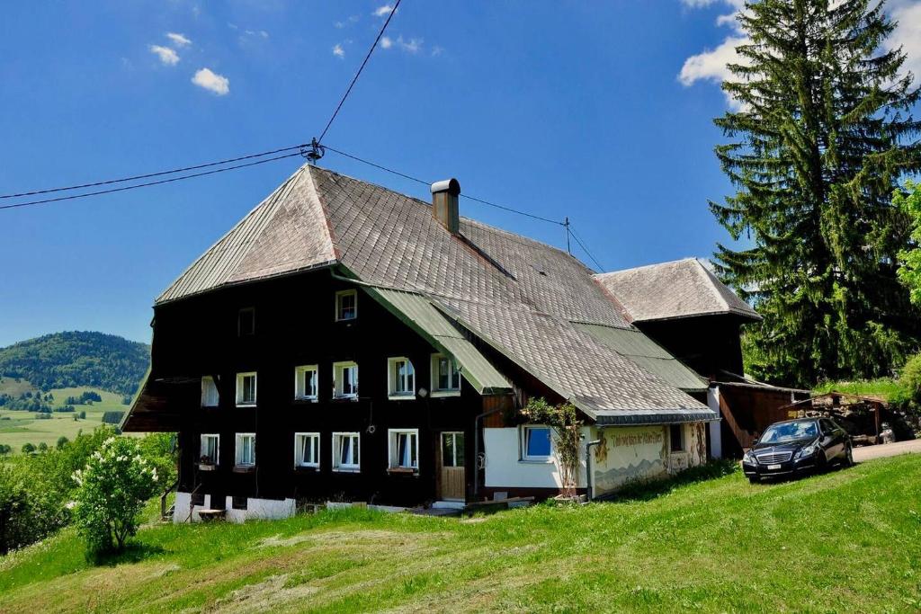ein schwarzes Haus auf einem Hügel mit einem Auto vor dem Haus in der Unterkunft Echtes Schwarzwaldhaus - Traditionell & Modern in Bernau im Schwarzwald