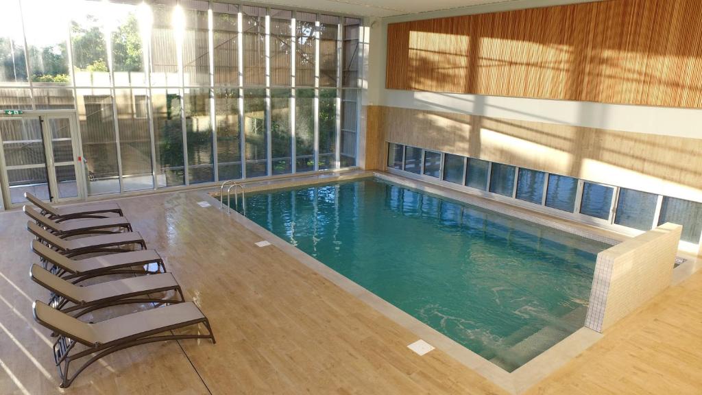 - une piscine avec des chaises longues dans un bâtiment dans l'établissement VVF Aveyron Najac, à Najac
