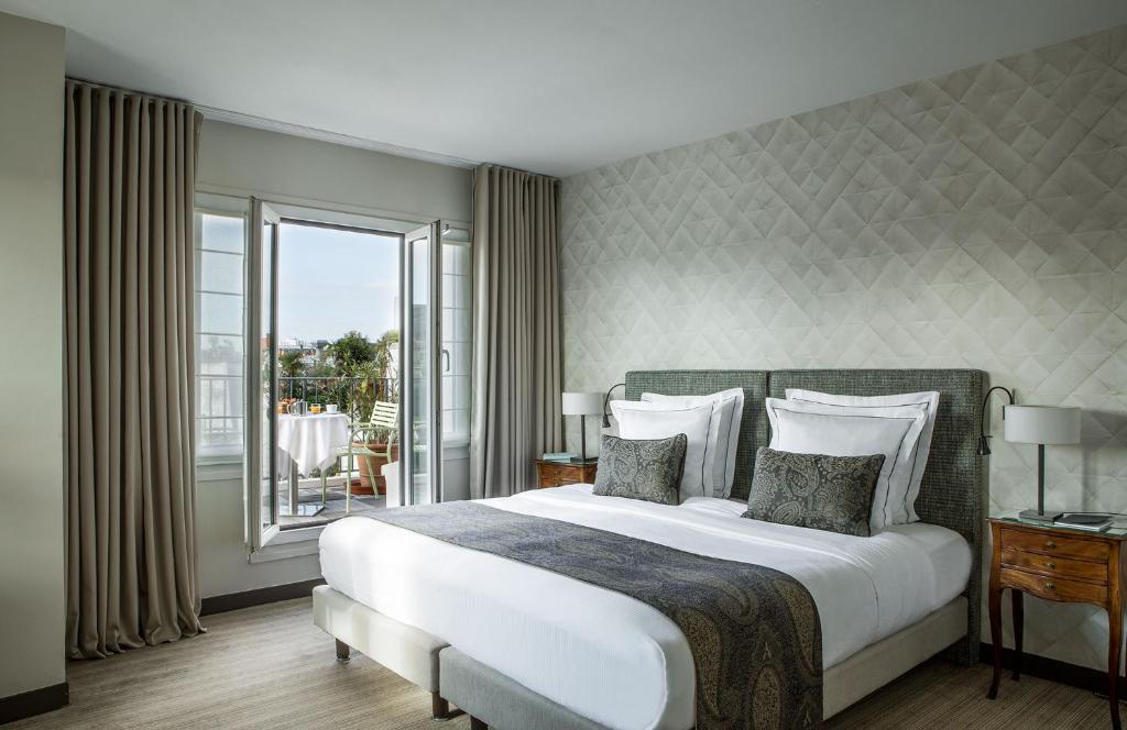 um quarto com uma grande cama branca e uma varanda em Hôtel Parc Saint-Séverin - Esprit de France em Paris