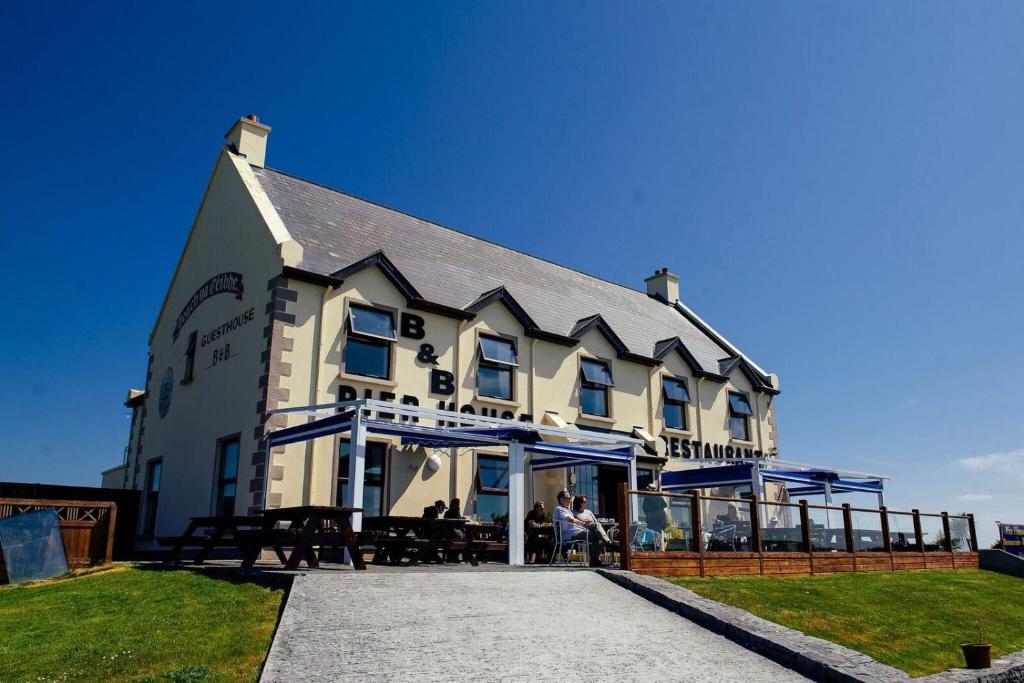 a large white building with people sitting outside of it at Pier House Bed & Breakfast in Inis Mor