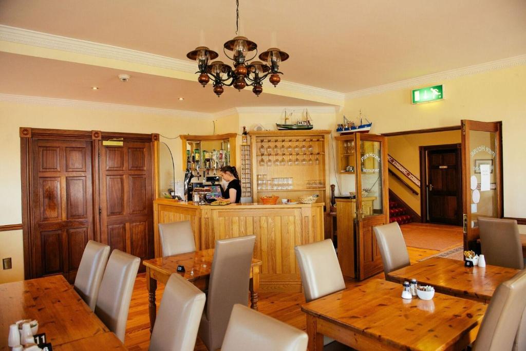a dining room with two tables and a woman in a kitchen at Pier House Bed & Breakfast in Inis Mor