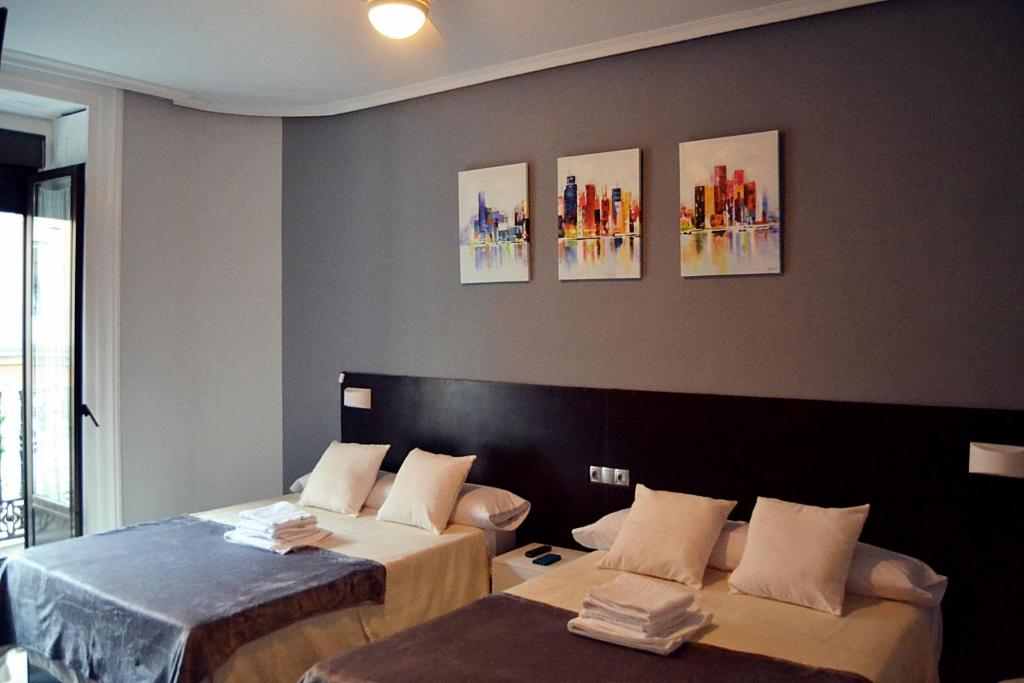 Habitación con 2 camas y pinturas en la pared. en Habitaciones Universal, en Madrid