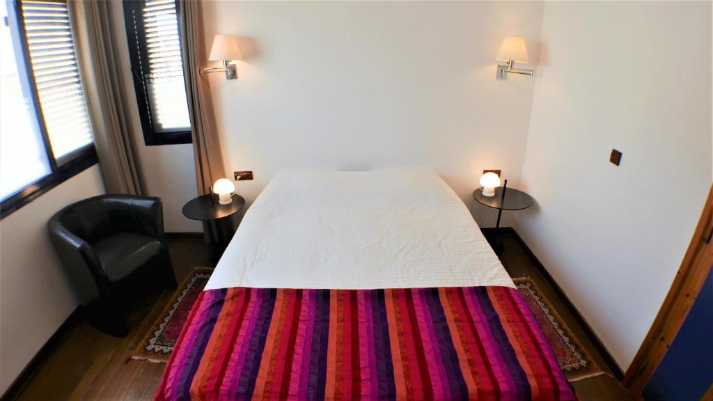 a bedroom with a bed with a colorful blanket on it at logis la marine in Sidi Ifni