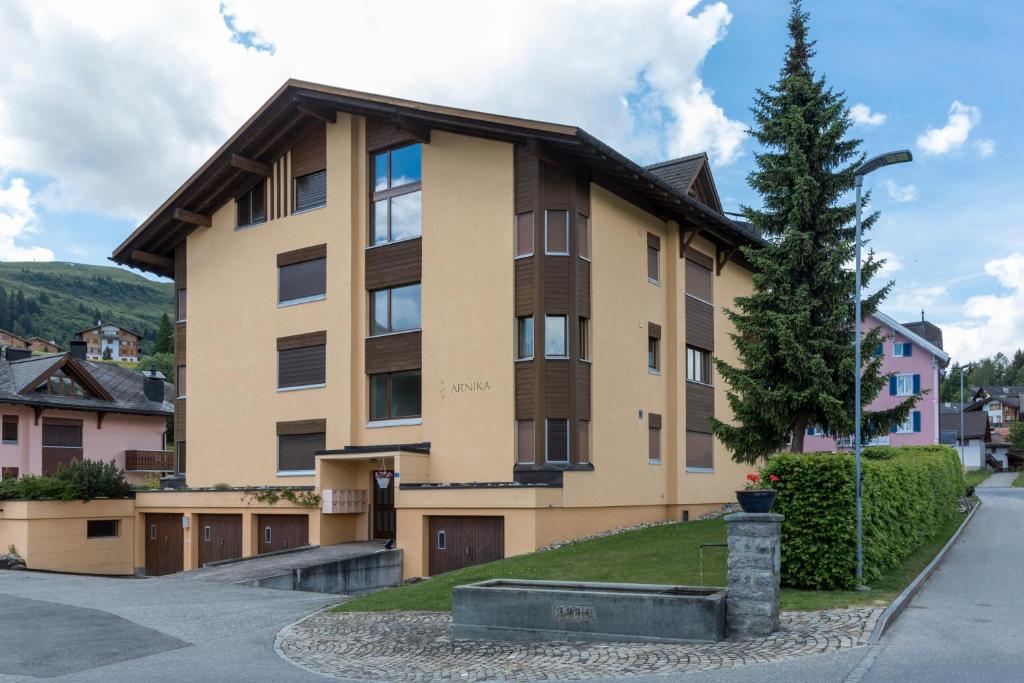 een groot appartementencomplex met een boom ervoor bij Apartment Haus Arnika in Obersaxen