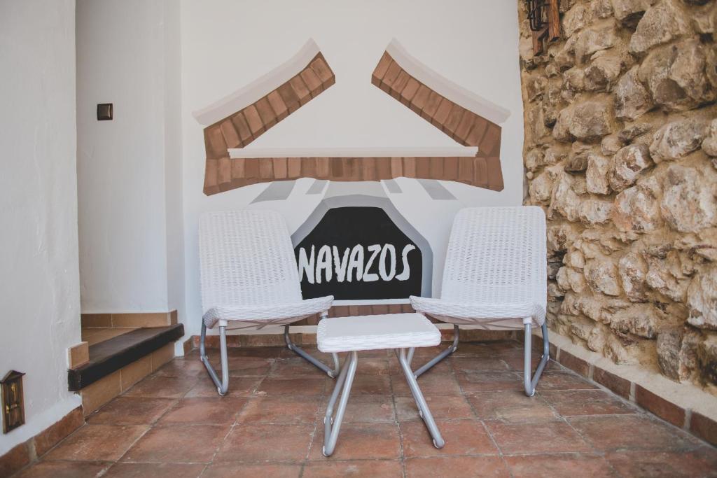 a group of three white chairs sitting next to a wall at Navazos loft in Benaocaz