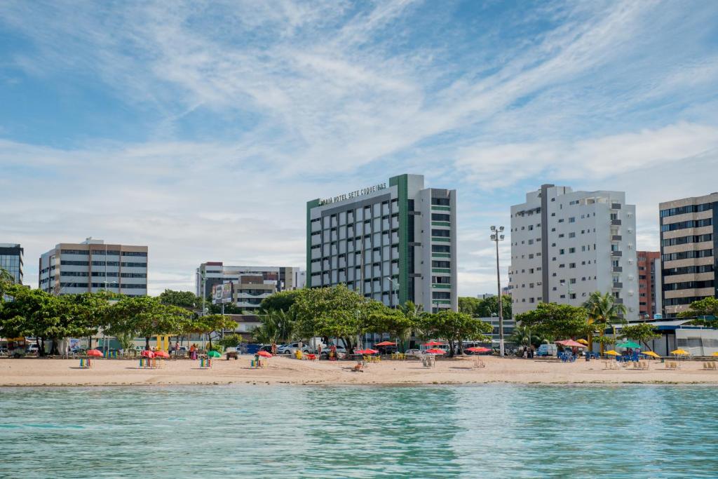 ein Strand mit Menschen und Sonnenschirmen in einer Stadt in der Unterkunft Hotel Sete Coqueiros in Maceió