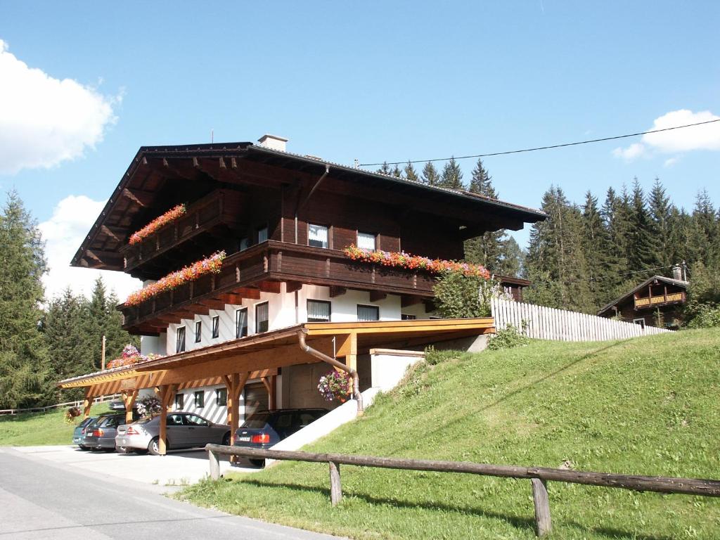 un edificio en una colina con coches estacionados frente a él en Appartementhaus zur Loipe en Sankt Jakob in Defereggen