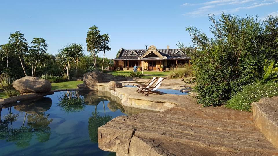 a house with a pond in front of it at Rockwood Earth Lodge in Champagne Valley