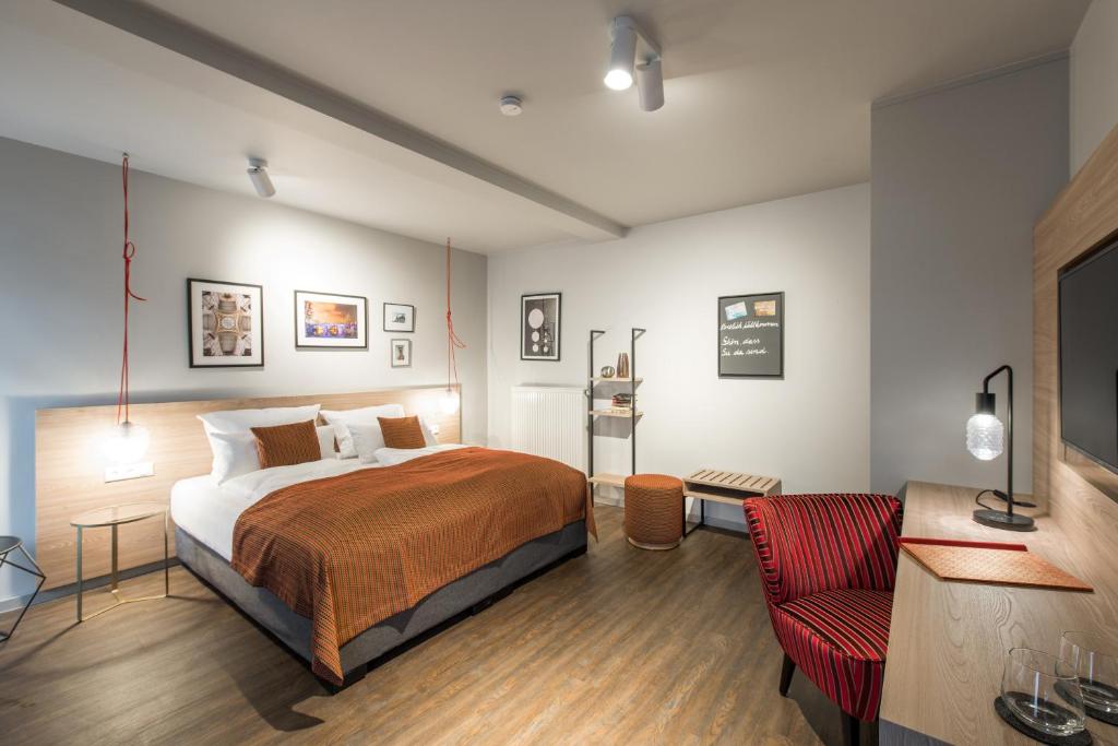 1 dormitorio con 1 cama y 1 silla roja en stattHotel Weimar en Weimar