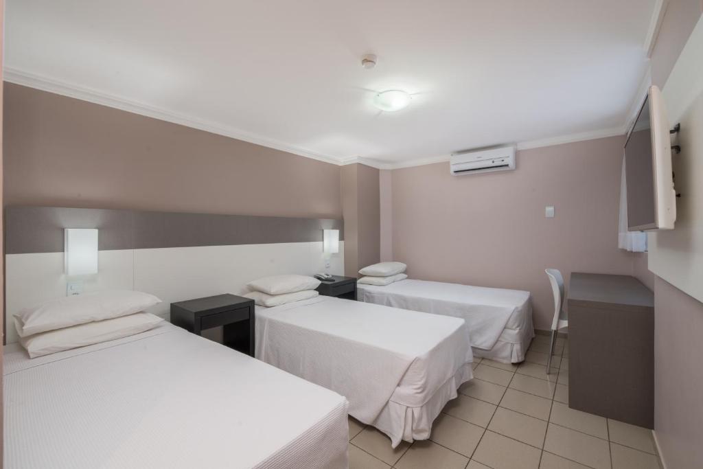 a hotel room with two beds and a table at Hotel Sete Coqueiros in Maceió