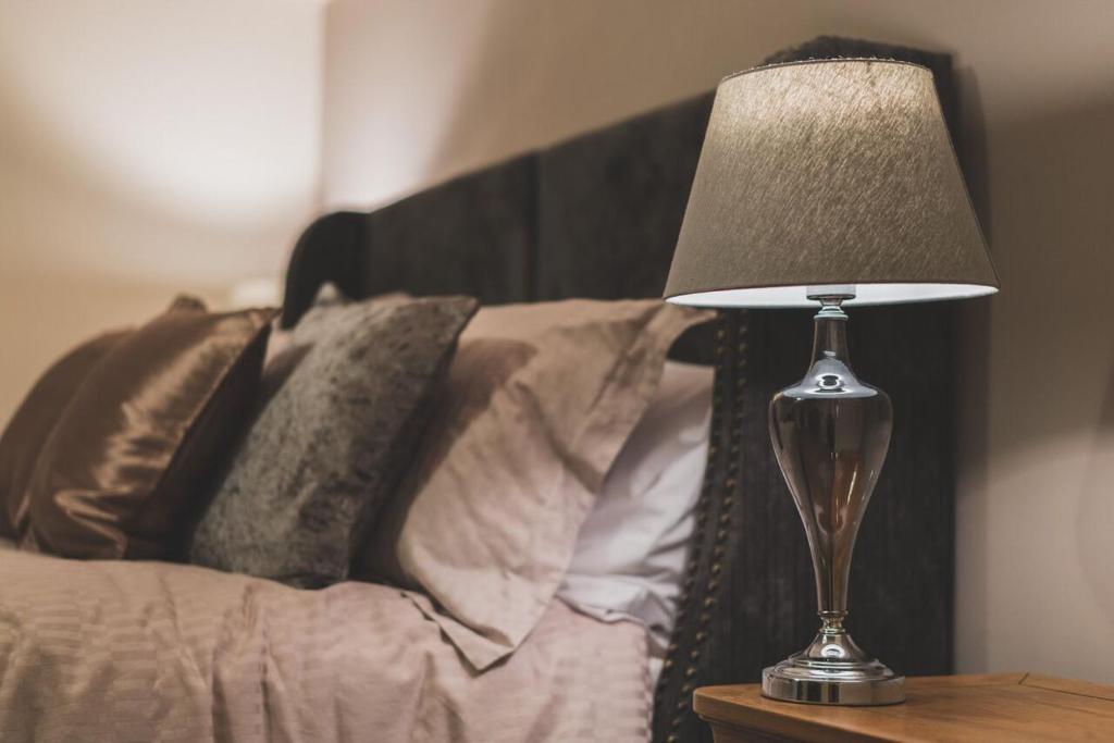 a lamp sitting on a table next to a bed at Anchor House in Alford