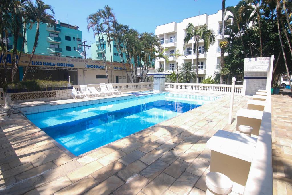 une piscine avec des chaises et un bâtiment dans l'établissement Paramar, à Ubatuba