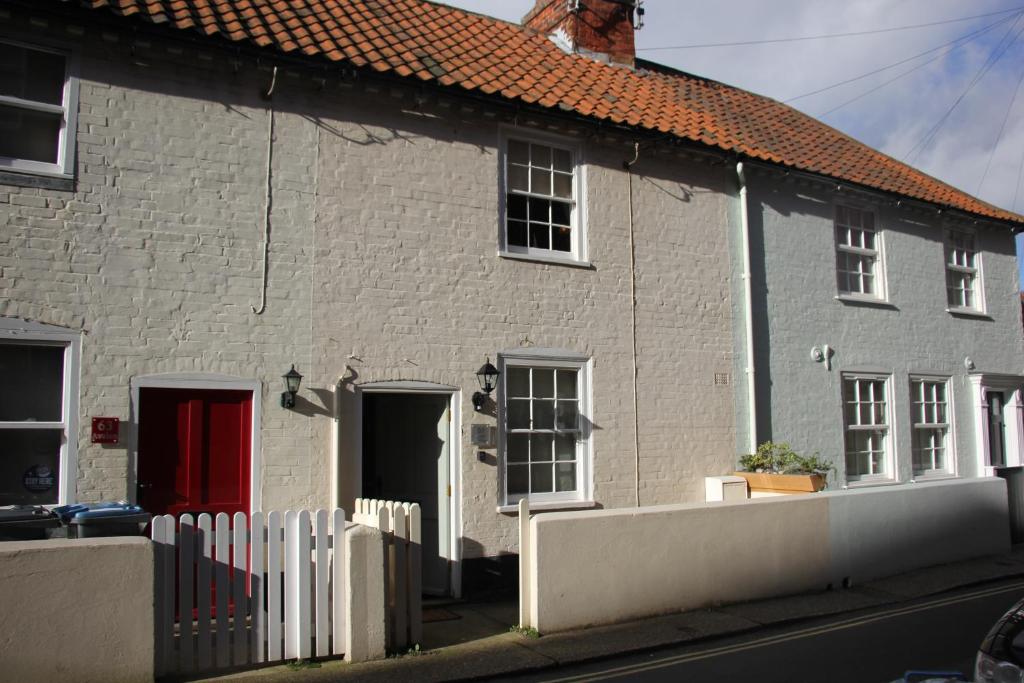 ein weißes Backsteinhaus mit einer roten Tür in der Unterkunft Seaside Fisherman Cottage Aldeburgh in Aldeburgh