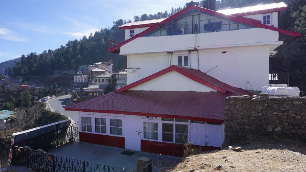 a white building with a red roof on a hill at Homely Feel like stay in Kufri-Shimla in Shimla