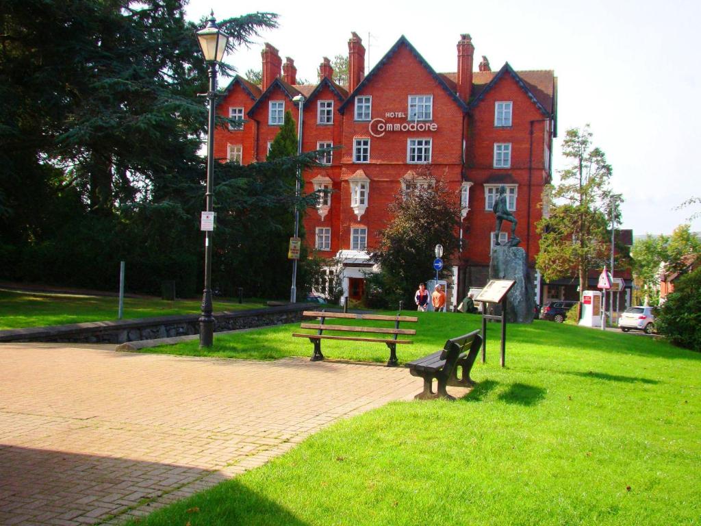 a park with a bench in front of a building at The Hotel Commodore in Llandrindod Wells