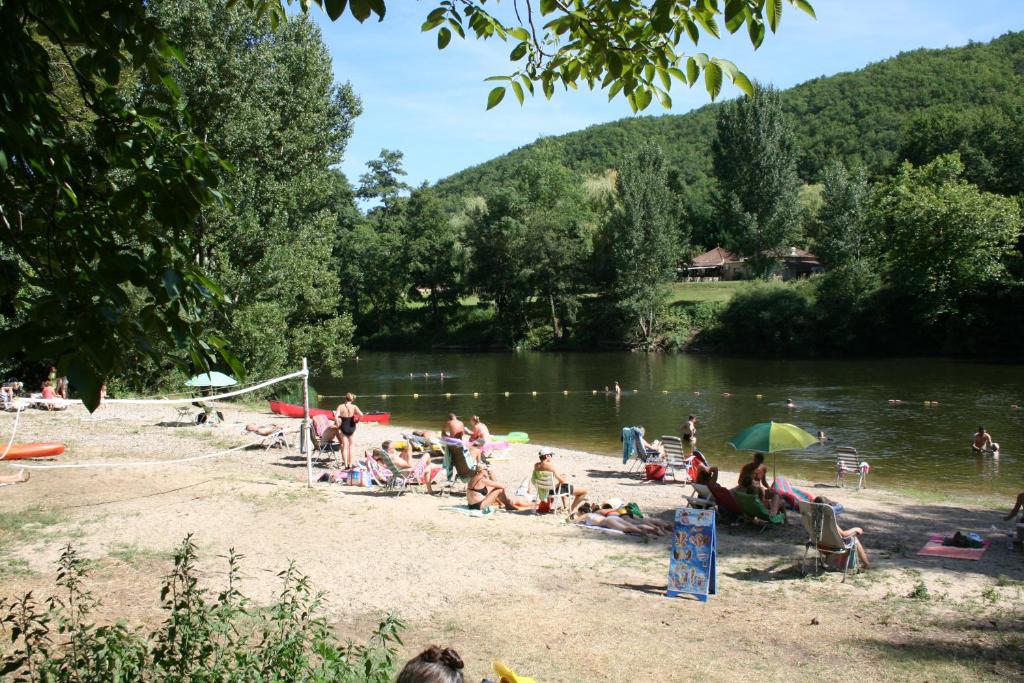 un grupo de personas en una playa cerca de un río en Village Camping Les Vignes, en Puy-lʼÉvêque