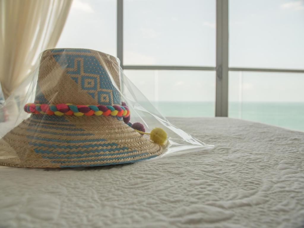 un sombrero de paja sentado en la parte superior de una cama en Luxury Alojamientos Namaste-Morros City, en Cartagena de Indias