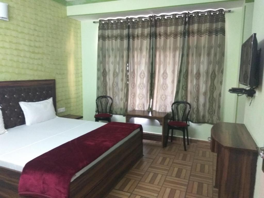 a bedroom with a bed and a tv and curtains at Peaceful & scenic Homestay in Shoghi-Shimla in Shimla