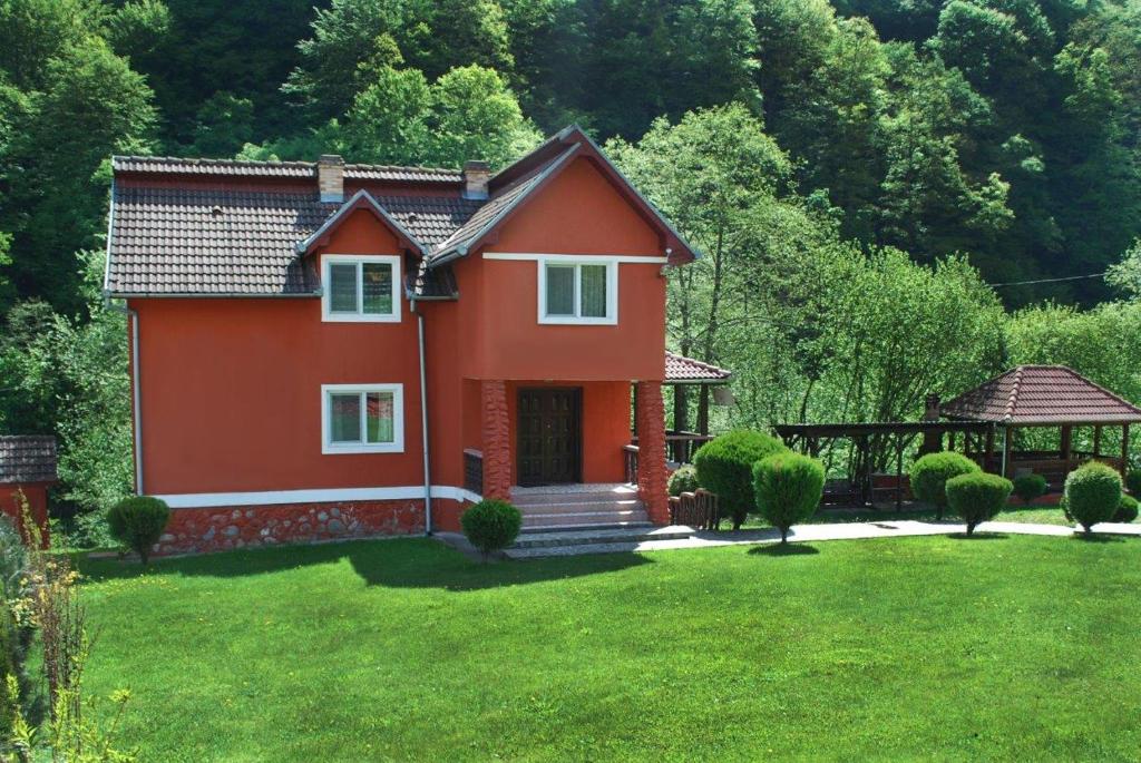 een klein rood huis in een tuin met een tuinhuisje bij Casa Retezat in Rîu de Mori