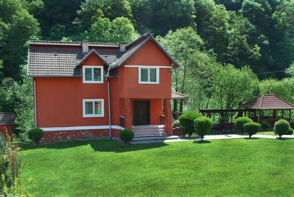 una pequeña casa roja en un patio con cenador en Casa Retezat, en Rîu de Mori