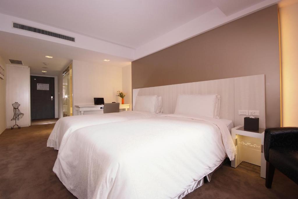 a bedroom with a large white bed and a desk at Forward Hotel Taipei Nangang in Taipei