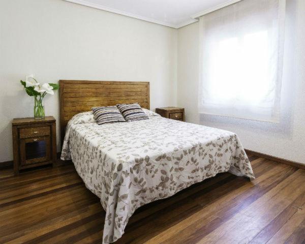 a bedroom with a bed with a blanket and a window at Apartamentos Cotiello in Llanes