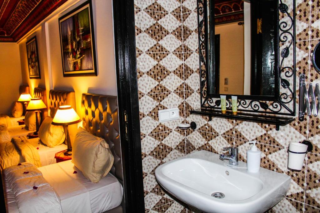 a bathroom with a sink and a bed and a mirror at Riad Challa Hotel & Spa in Marrakesh