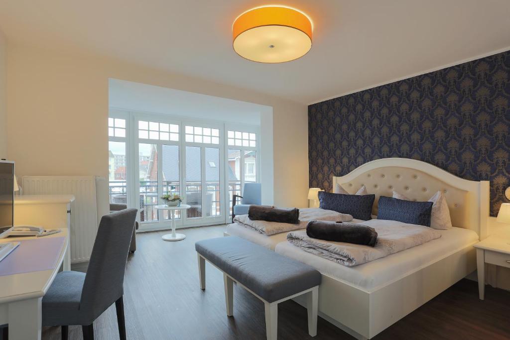 a bedroom with a large white bed with blue pillows at Hotel Strandvilla Janine in Borkum