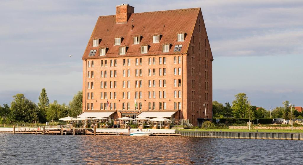 ein großes Backsteingebäude neben einem Wasserkörper in der Unterkunft Hotel Speicher am Ziegelsee in Schwerin