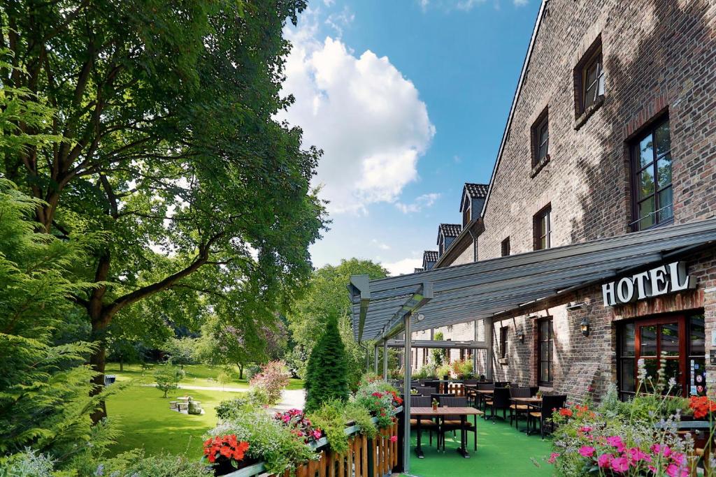 ein Hotel mit Tischen und Stühlen außerhalb eines Gebäudes in der Unterkunft Landhaus Danielshof in Bedburg