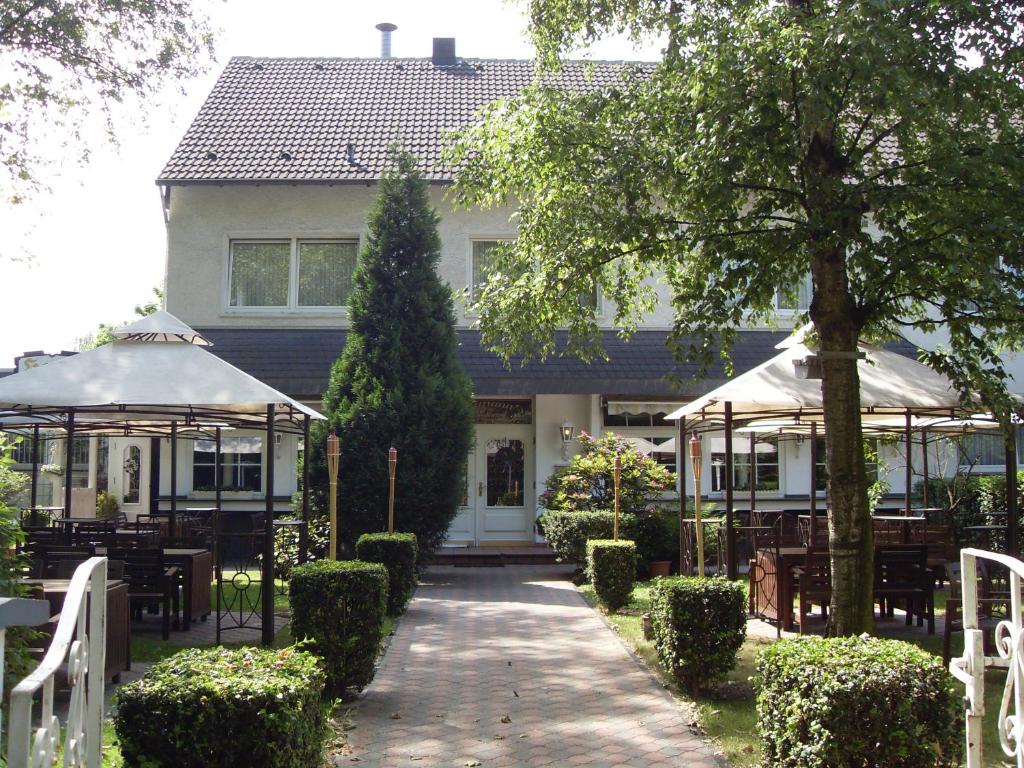 a house with tables and umbrellas in front of it at Hotel am Stadion in Duisburg