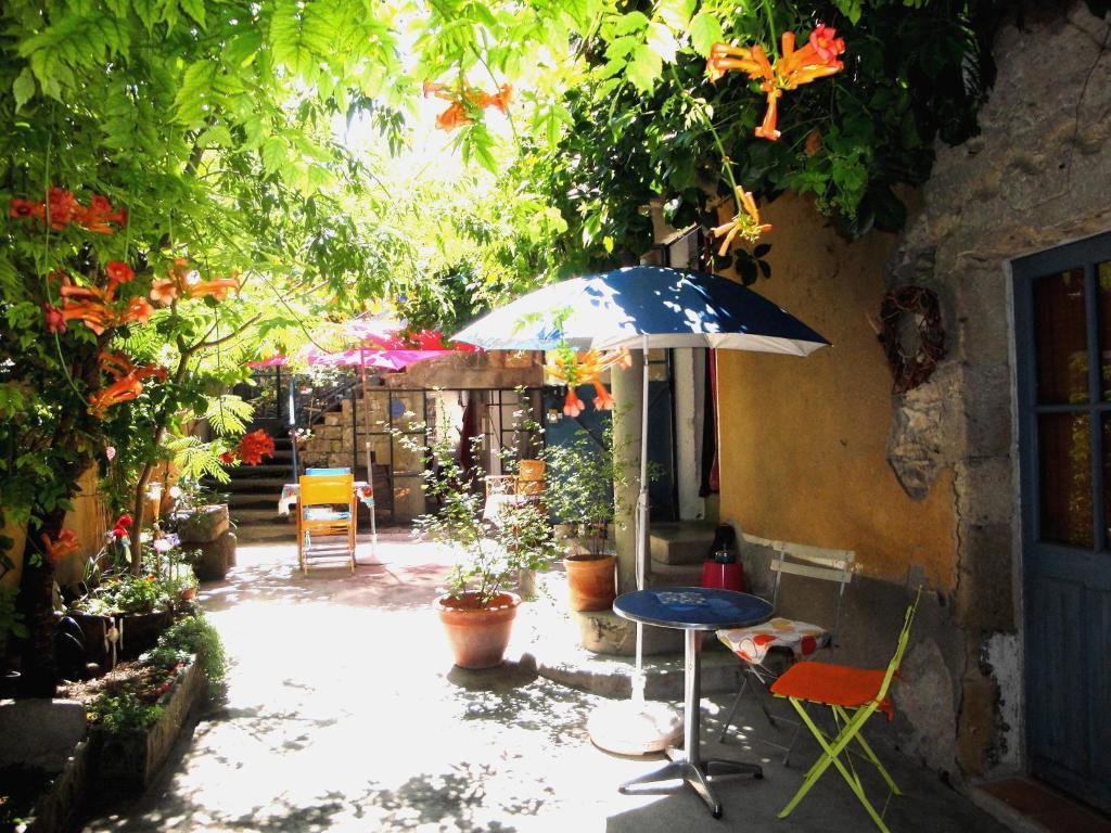 a patio with an umbrella and a table and chairs at Chez Clairotte in Salinelles