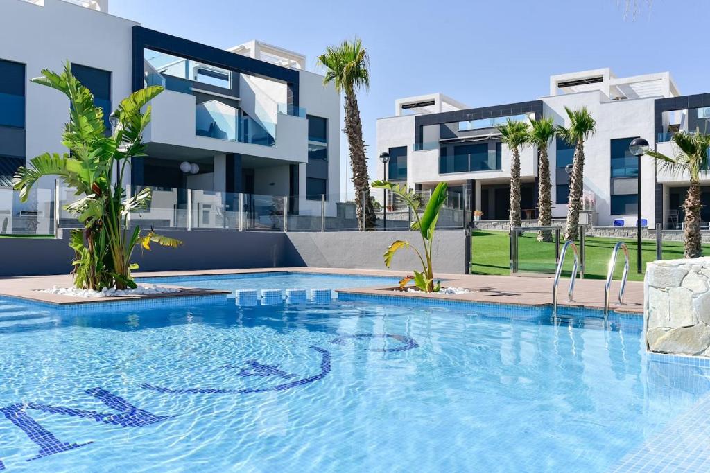 una piscina frente a un edificio con palmeras en Oasis Beach IX PuntaPrima, en Torrevieja